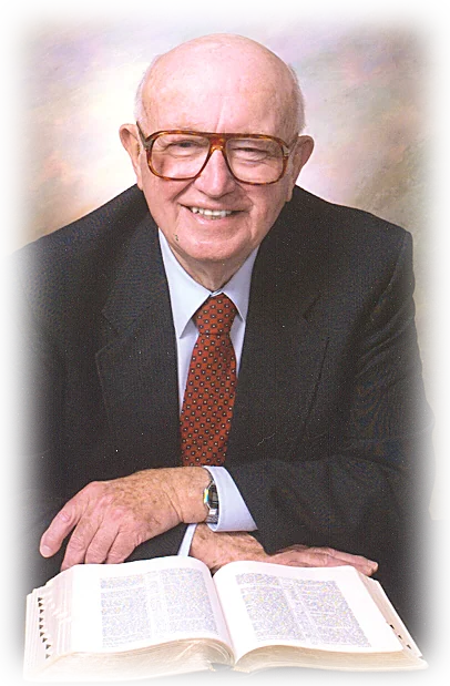 William MacDonald, smiling, with an open Bible in front of him