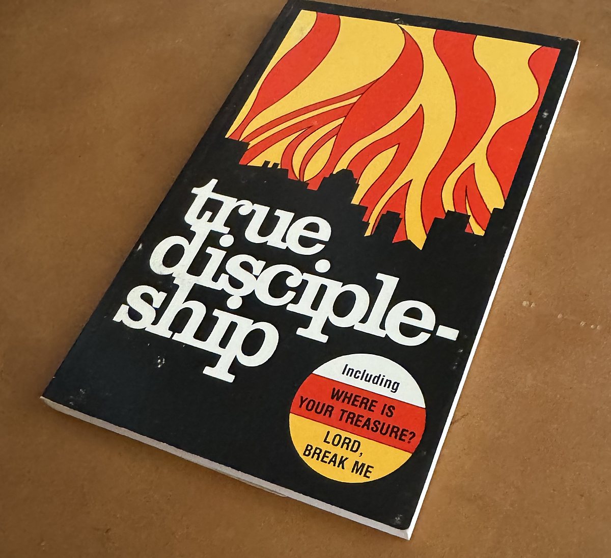 Cover of True Discipleship by William MacDonald: flames over a city skyline, with a badge reading Including Where Is Your Treasure? and Lord, Break Me