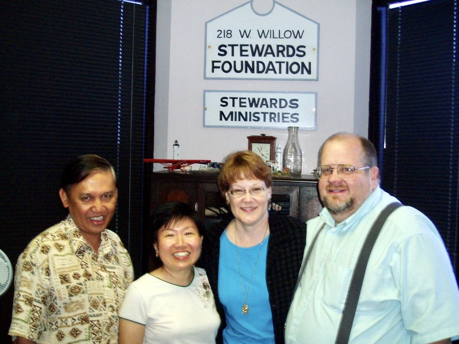 The same visit: the guests from Singapore with Cheryl and Kevin (right), under the 218 W. Willow and Stewards Ministries signs. Stewards Foundation and Stewards Ministries once shared the 218 West Willow office in Wheaton, Illinois. When the Foundation moved to Texas, these signs came with it as a keepsake of those years.