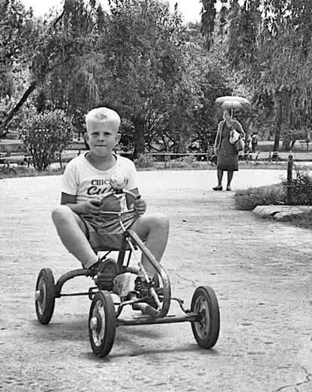Si Kevin Engle sa edad na mga labing-isa, nakasuot ng T-shirt ng Chicago Cubs, sakay ng pedal go-kart sa isang daan sa Burnham Park, Lungsod ng Baguio